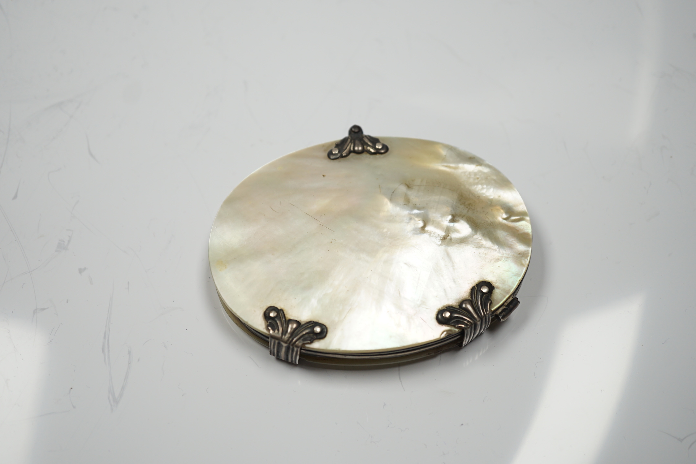A 19th century white metal and mother of pearl mounted oval folding magnifying glass (a.f.), 90mm.